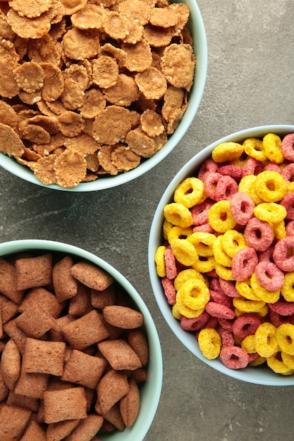 Variety of cereals in blue bowls, quick breakfast on grey background. Vertical photo