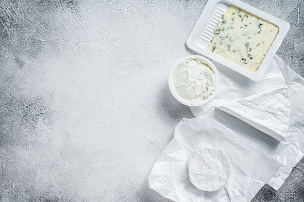 Variety of cheese kinds on kitchen table, brie, Camembert, Gorgonzola and blue creamy cheese.