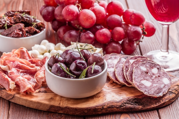 Variety of cheese and meat on dark table.