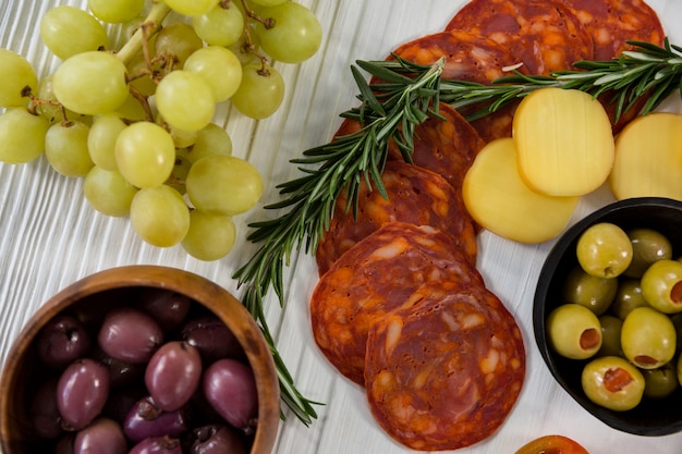 Variety of cheese with grapes, olives, salami, and crackers