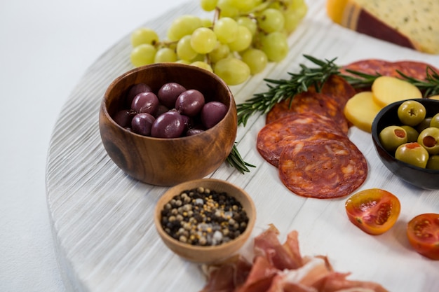 Variety of cheese with grapes, olives, salami and crackers