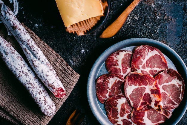 Variety of cheeses and sausages typical of Spain on vintage wooden table. Sheep cheese, fuet, sausage, chorizo. Spanish food. Free space for text. Top view.