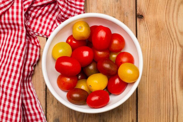 Variety of cherry tomatoes  in a white bowl on a wooden table