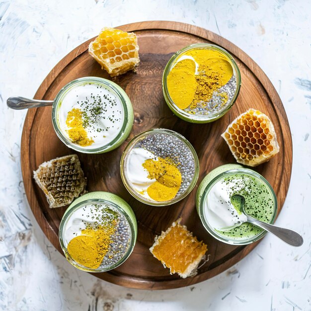 Variety of chia puddings with turmeric matcha powder and yogurt in glass jars served on wooden board