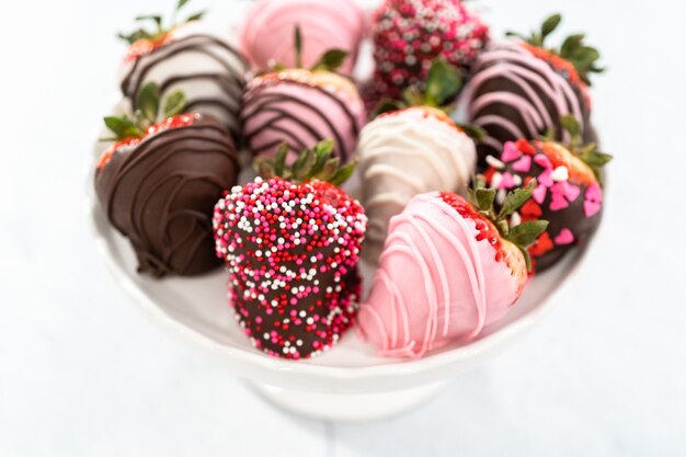 Variety of chocolate dipped strawberries on a cake stand.