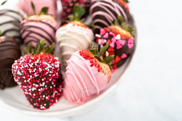 Variety of chocolate dipped strawberries on a cake stand.