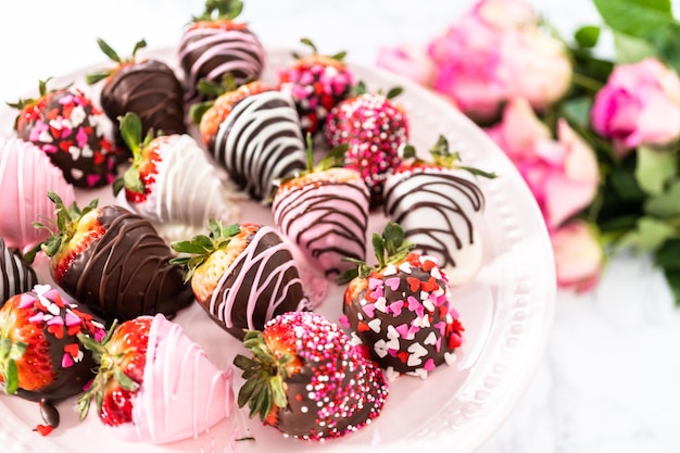 Variety of chocolate dipped strawberries on a pink cake stand.