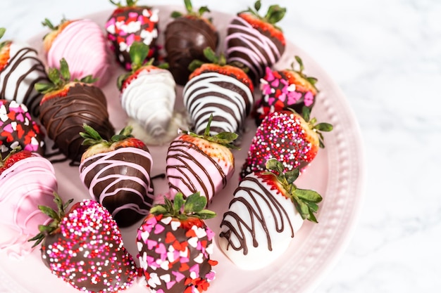 Variety of chocolate dipped strawberries on a pink cake stand