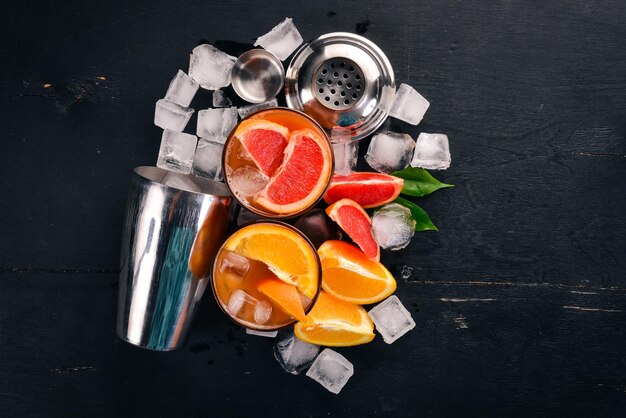 A variety of cocktails of whiskey orange and grapefruit juice Negroni On a wooden black background Top view Copy space