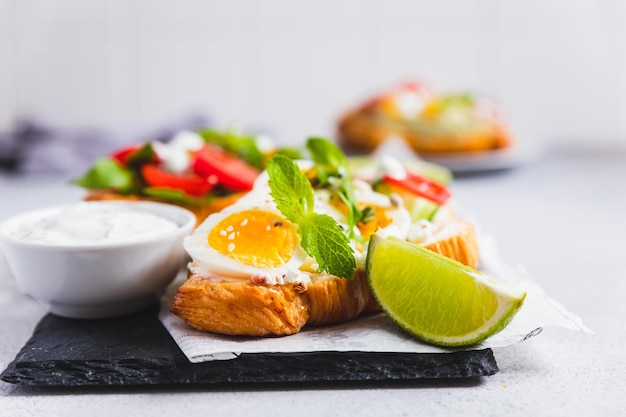 Variety of croissant sandwiches with tomato cucumber mozzarella eggs and avocado mint and arugula