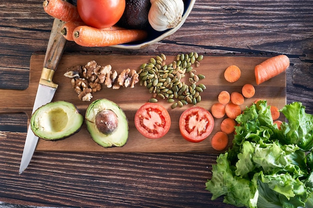 Variety of cut vegetables for a salad on vintage wooden background. Healthy vegetarian food, top view.