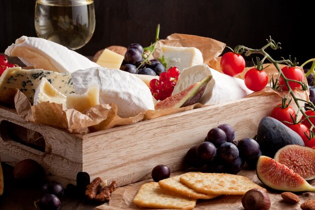 Varietà di formaggi diversi con vino, frutta e noci.