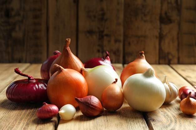 Variety of different onions on wooden table