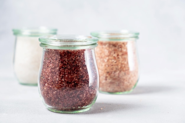 Variety of different salt in glass jars on gray background