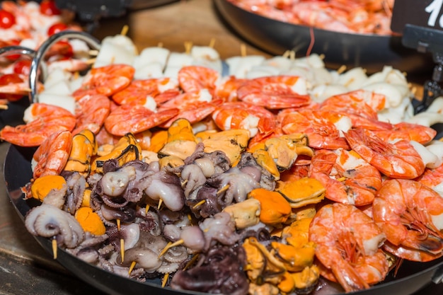 Variety of different savory seafood on display in tray at a market stall or catered event, food and beverage concept