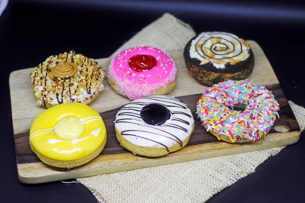 A variety of donuts are on a wooden tray.