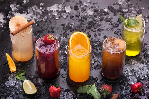 A variety of drinks are lined up on a table with ice and strawberries.