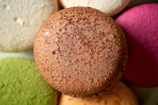 Variety of flavors of macaroon pastries in a white plate on a wooden background. Close up, selective focus