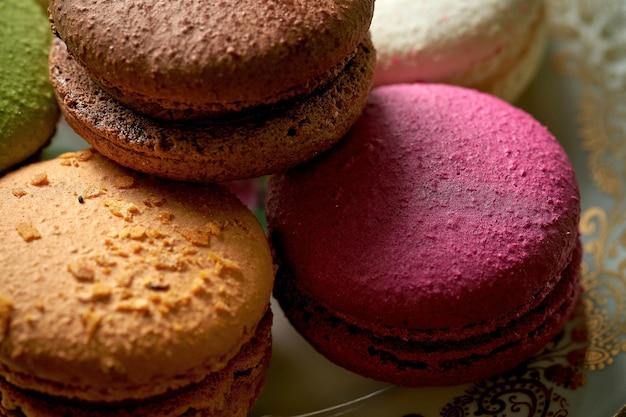 Variety of flavors of macaroon pastries in a white plate on a wooden background. Close up, selective focus