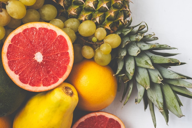 Foto varietà di frutta fresca su una piattaforma su sfondo bianco.