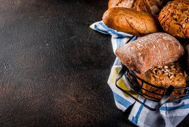 Variety of fresh homemade grain bread, in a metal basket, dark rusty  copyspace