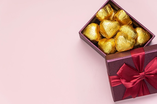 Variety of gifts and chocolates in the shape of a golden heart isolated pink background Valentine39s concept