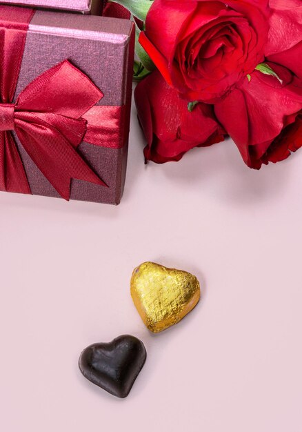 Variety of gifts and chocolates in the shape of a golden heart isolated pink background Valentine39s concept