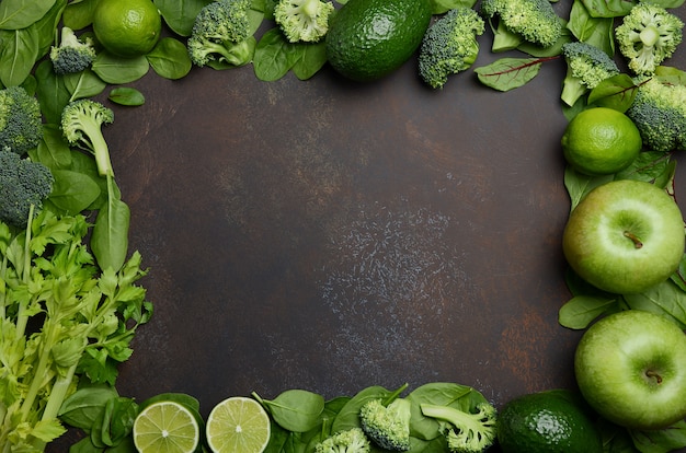 Variety of green fruits and vegetables on a dark concrete