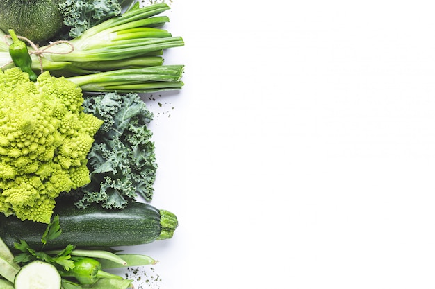 Variety of green vegetables on white background with copy space. Top view.