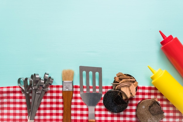 Variety of grilling tools on blue background.