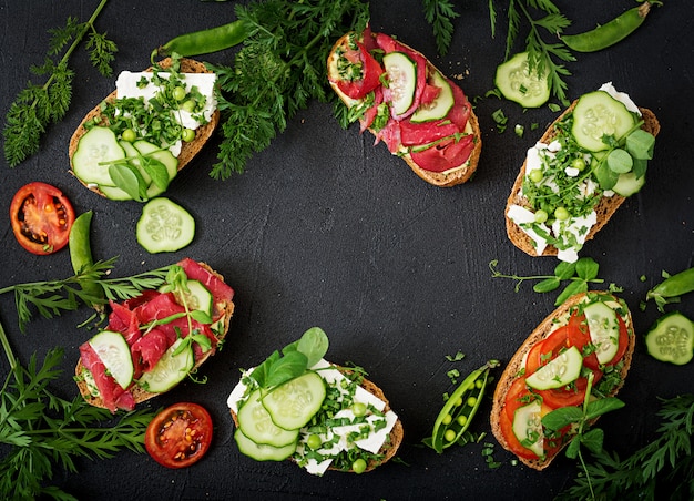 Variety of healthy sandwiches on a dark table in a rustic style. . Flat lay