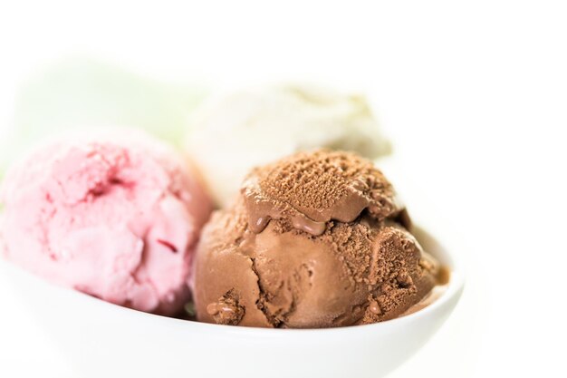 Variety of ice cream scoops in a white bowl.