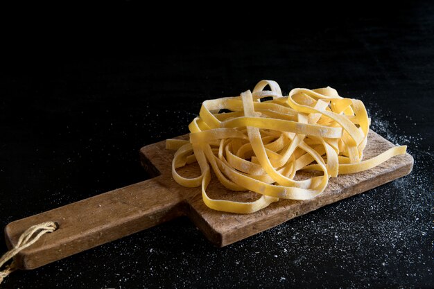 A variety of Italian homemade raw uncooked tagliatelle pasta on a cutting board