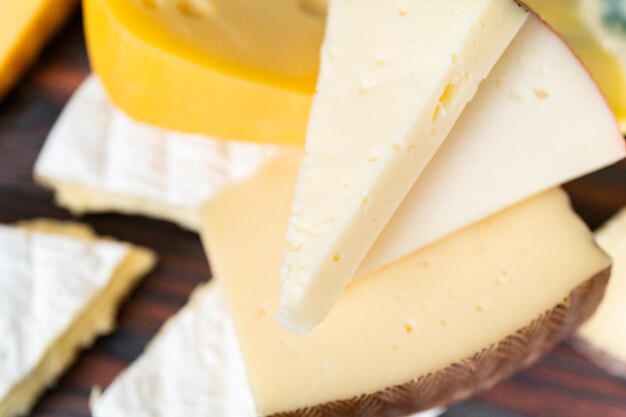 Variety of large gourmet cheese wedges on a dark wooden background.