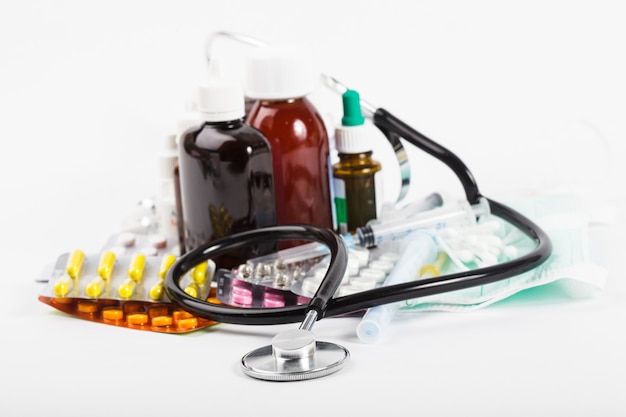 A variety of medicine and stethoscope on white background