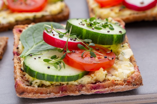 Variety of mini sandwiches with cream cheese, vegetables and salami