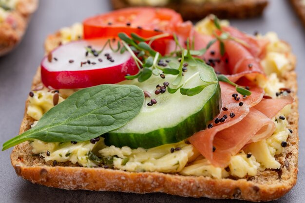 Variety of mini sandwiches with cream cheese, vegetables and salami.