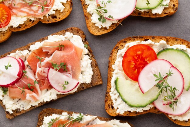 Variety of mini sandwiches with cream cheese, vegetables and salami.