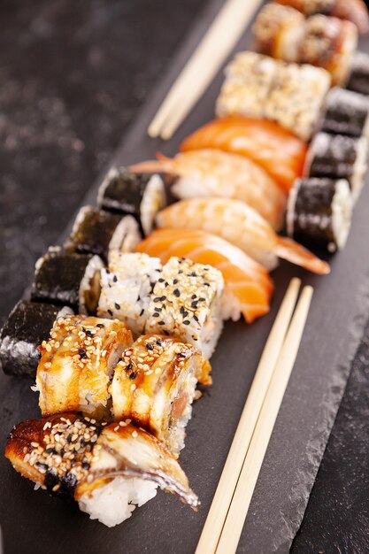 Variety mix of sushi rolls on black background in studio photo