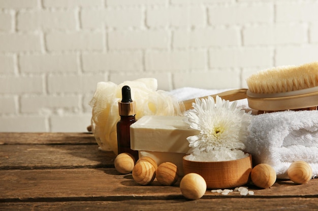 Variety of natural bath tools on wooden table on bricks wall background