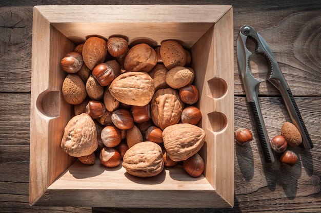 Variety of nuts with nutcracker on wooden background with metal nutcracker