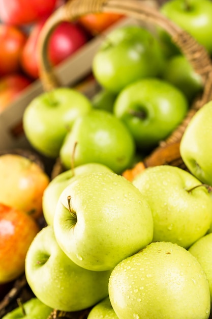 Variety of organic apples in baskets on wood table.