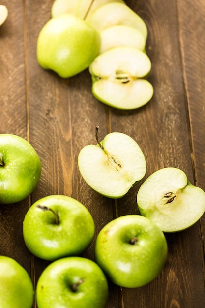 Variety of organic apples sliced on wood table.