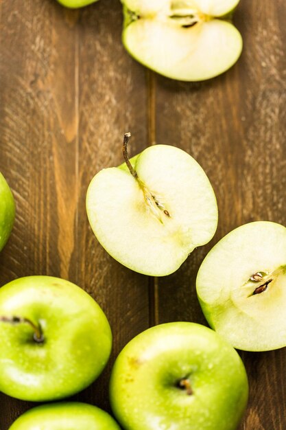 Variety of organic apples sliced on wood table.