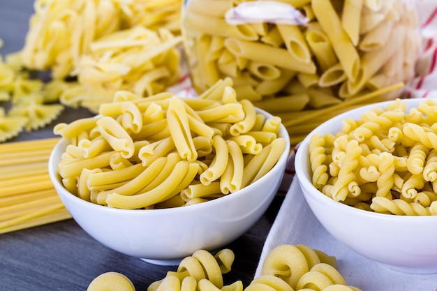 Variety of organic dry pasta on wood board.