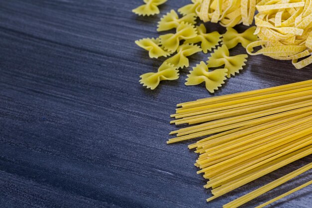 Variety of organic dry pasta on wood board.