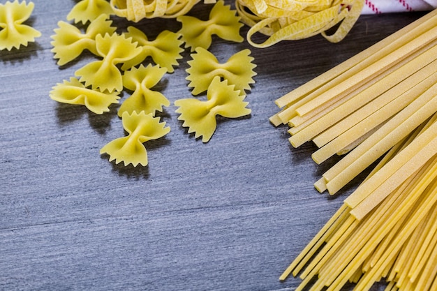 Variety of organic dry pasta on wood board.