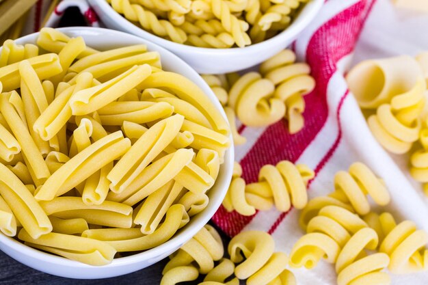 Variety of organic dry pasta on wood board.