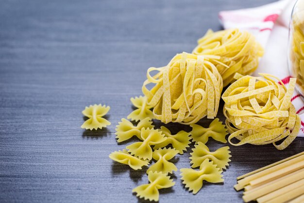 Variety of organic dry pasta on wood board.