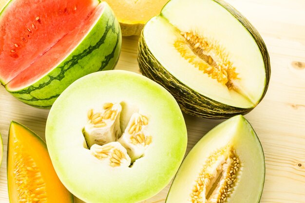 Variety of organic melons sliced on wood table.